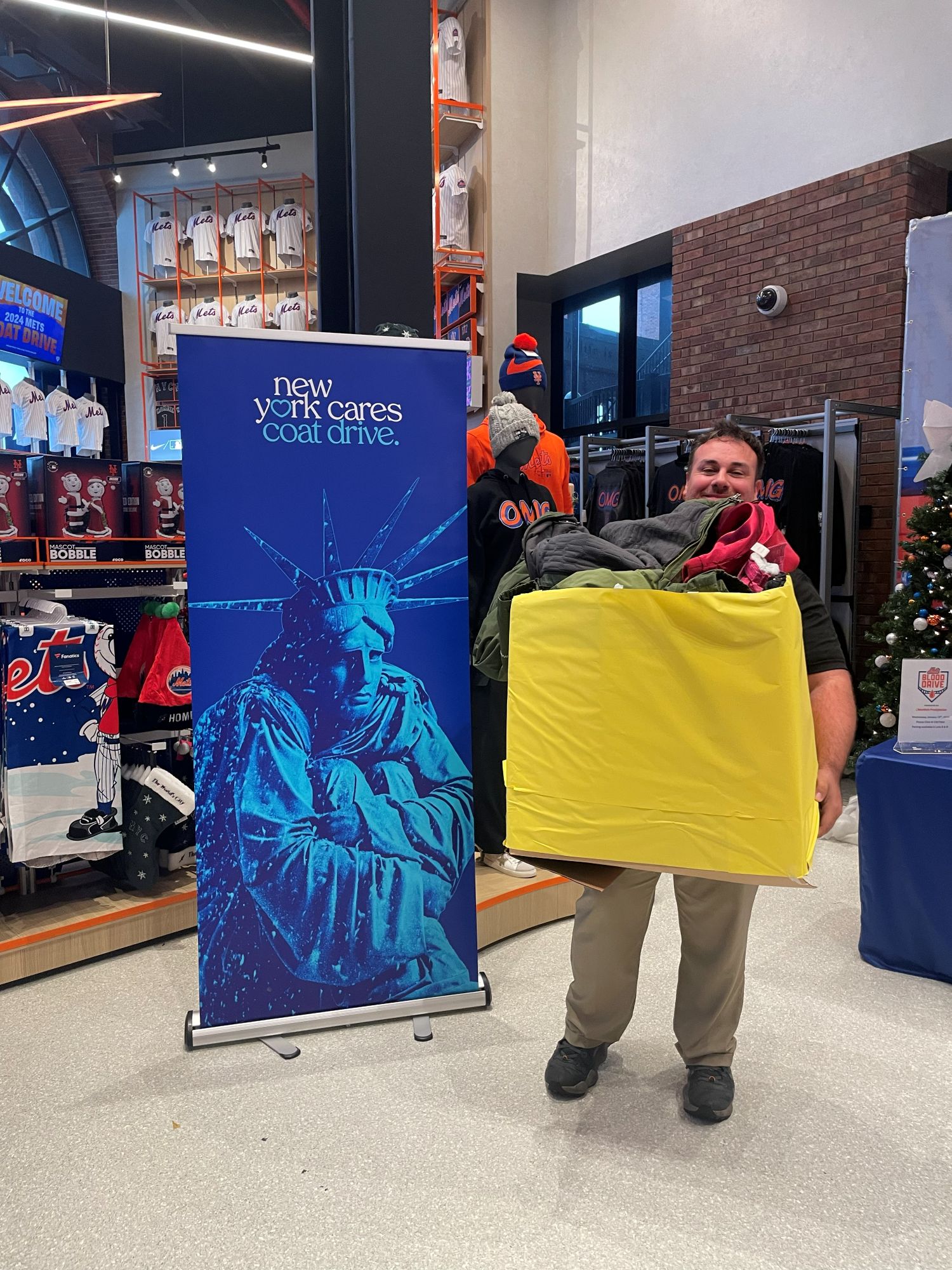 Volunteer holding box of coats at Mets Coat Drive